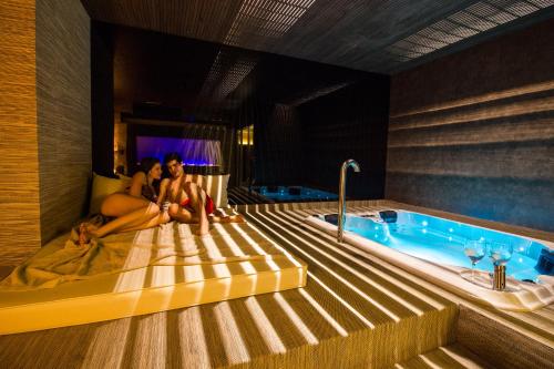 two women sitting on a bed next to a tub at Hotel Spa Balfagon in Cantavieja