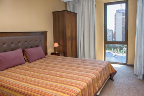 ein Schlafzimmer mit einem großen Bett und einem großen Fenster in der Unterkunft Royal Beach Apartments in Sonnenstrand