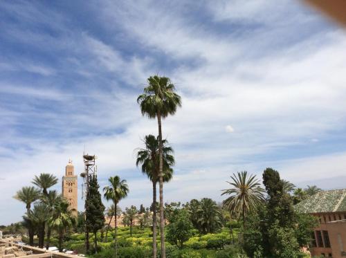 a clock tower and palm trees in front of a building at Chems Hotel in Marrakech