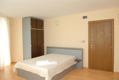 1 dormitorio con 1 cama y puerta de madera en Family Hotel Bistritsa en Sandanski