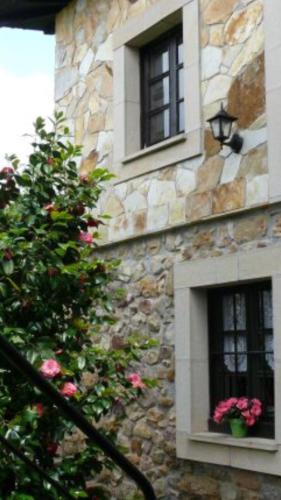 a stone building with two windows with pink flowers at La Casina de Celorio in Celorio