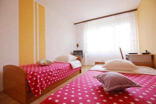 - 2 lits dans une chambre dotée d'une couverture rouge en point de polka dans l'établissement Apartment Angela, à Zadar