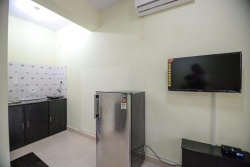 a room with a refrigerator and a flat screen tv on the wall at Sunshine Park Homes in Colva