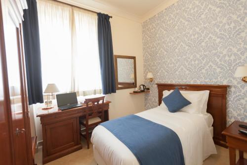 a hotel room with a bed and a desk with a laptop at Relais Villa Giuliana in Licata