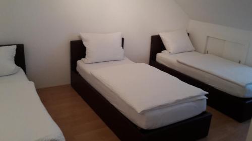 two beds in a small room with white sheets at Pension Harleshausen in Kassel