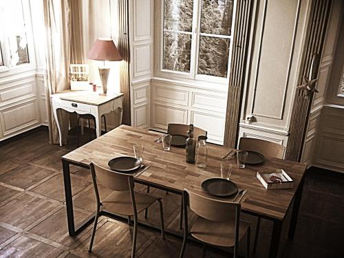 een houten tafel in een kamer met stoelen en een bureau bij le bal d'arsène in Aurillac