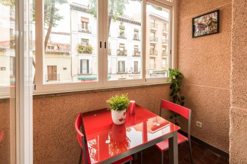 Apartamentos El Rastro في مدريد: طاولة حمراء عليها نبات الفخار بجوار النافذة