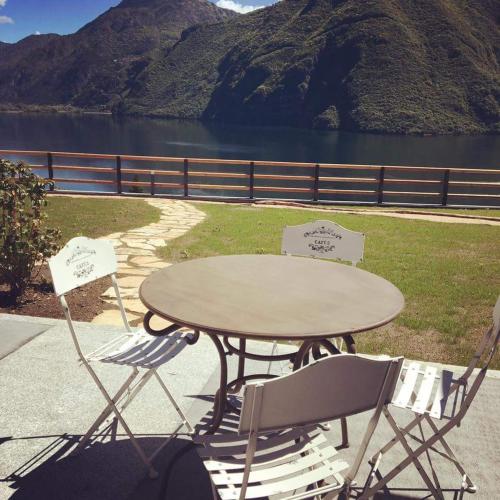 a table and two chairs sitting next to a lake at Rocca d'Anfo B&B-Apartments Lake View in Rocca dʼAnfo
