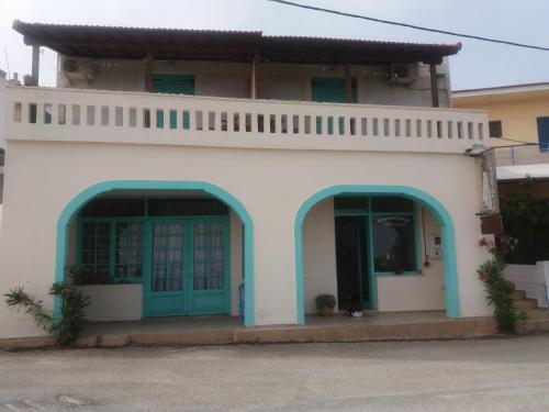 a white building with blue doors and windows at Ikosrooms in Votsi