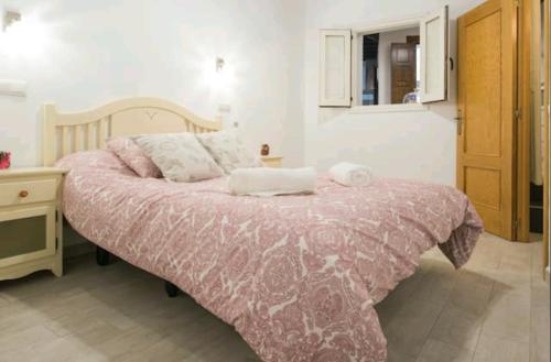 a bedroom with a bed with a pink comforter at Apartamento Tres Culturas in Toledo