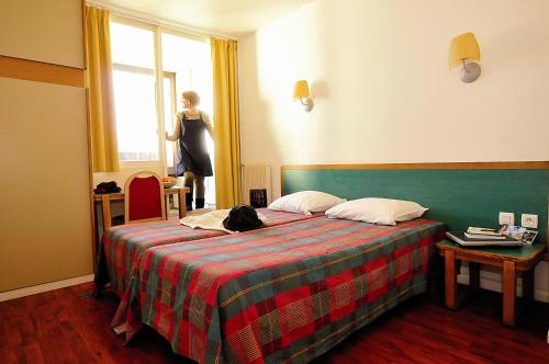 a woman standing in a hotel room with a bed at VTF Le Domaine des Puys in Saint-Sauves- dʼAuvergne