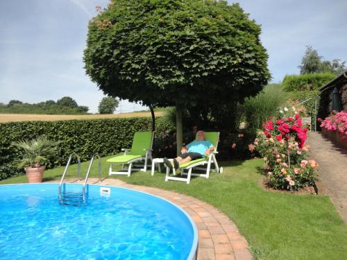 Ein Mann auf einem Stuhl neben einem Pool in der Unterkunft Gästehaus Nelles in Sinzig