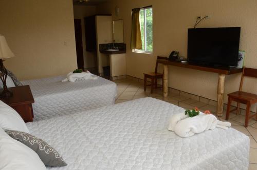 a hotel room with two beds and a flat screen tv at Lamanai Hotel & Marina in Orange Walk
