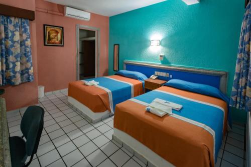 a hotel room with two beds and a chair at Hotel Acuario in Ciudad del Carmen