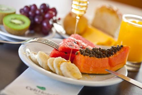 Un plato de fruta con un tenedor sobre una mesa. en Celi Hotel Aracaju, en Aracaju