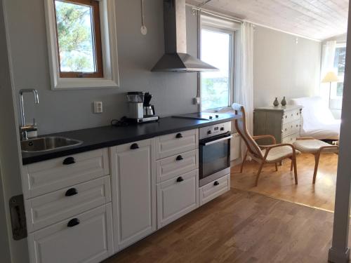 a kitchen with white cabinets and a sink at Idöborgs Stuguthyrning in Nämdö