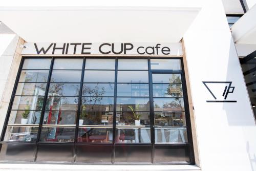 a white cup cafe sign on top of a building at White Luxury in Thessaloniki