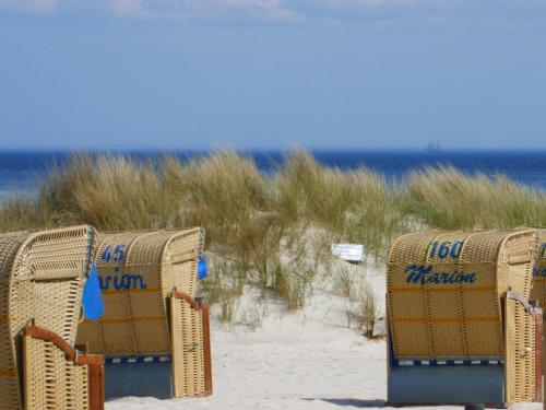 two chairs sitting in the sand on a beach at Haus Strandperle in Dahme