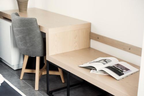 a wooden desk with a book and a chair at White Luxury in Thessaloniki
