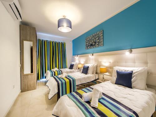 two beds in a room with blue walls at Bayside Apartments in St Julian's