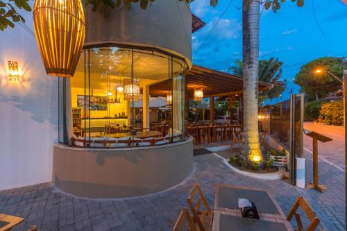 a restaurant with tables and chairs in front of a building at Porto Geraes Praia Hotel in Porto Seguro