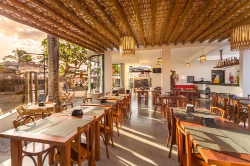 an empty restaurant with wooden tables and chairs at Porto Geraes Praia Hotel in Porto Seguro