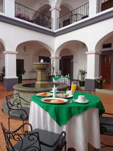 a table with a green table cloth and a fountain at Hotel del Marquesado in Oaxaca City
