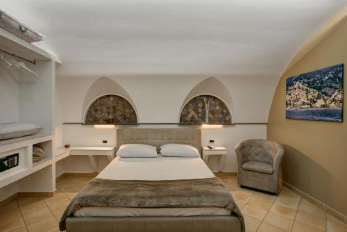 a bedroom with a bed and a chair and two windows at Cuore di Sorrento Suites in Sorrento