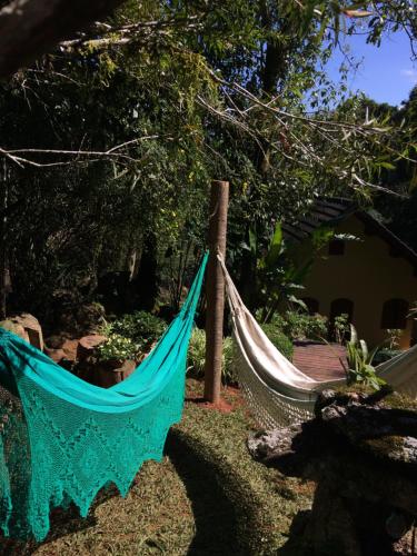 a hammock tied to a pole in a yard at Hospedagem Casadalee chalé com piscina privativa aquecida e Apartamento sem piscina in Monte Verde