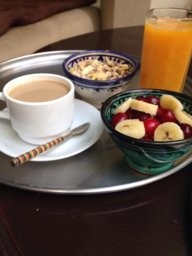 a tray with a bowl of fruit and a cup of coffee at Riad Tizwa Marrakech in Marrakech