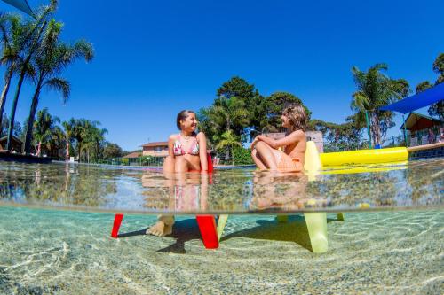 two children sitting on a table in the water at BIG4 Moruya Heads Easts Dolphin Beach Holiday Park in Moruya