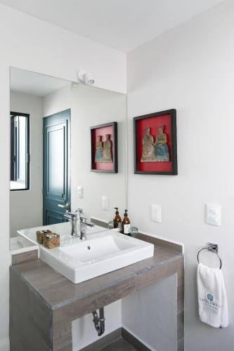a bathroom with a white sink and two pictures on the wall at La Palomilla Bed & Breakfast in Mexico City