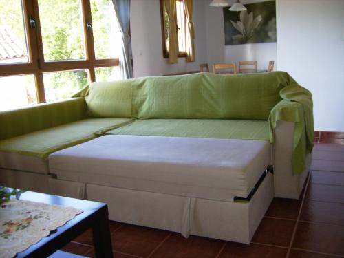 un sofá verde en una sala de estar con mesa en El Mirador de Valdedios " Casa Friera", en Puelles