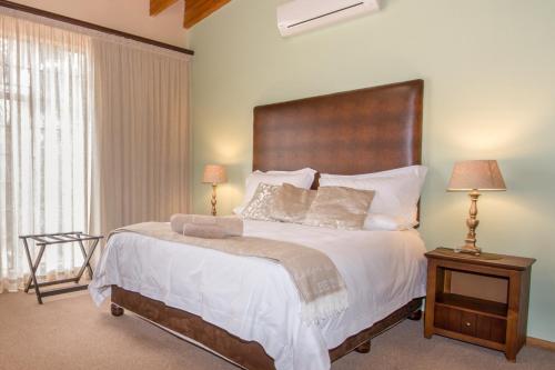 a bedroom with a large bed and two lamps on tables at Sunset Manor Guest House in Potchefstroom