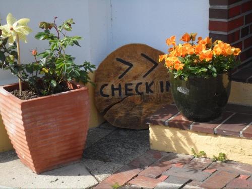 zwei Topfpflanzen sitzen neben einem Schild in der Unterkunft Frieslands Ferienwohnung in Bockhorn