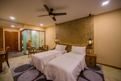 a bedroom with two beds and a ceiling fan at Kiha Beach in Dharavandhoo