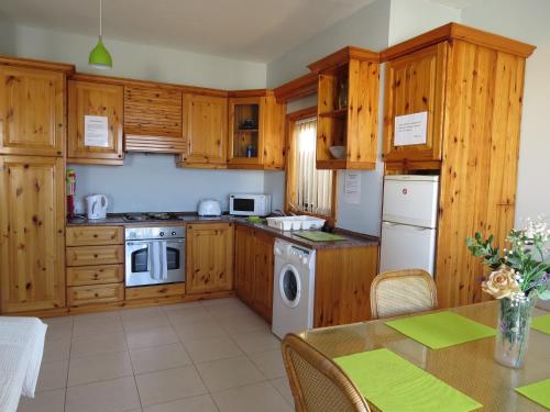 a kitchen with wooden cabinets and a table at Mellieha Holiday Apartment 1 in Mellieħa