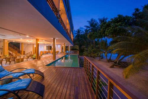 a resort deck with chairs and a swimming pool at Kiha Beach in Dharavandhoo