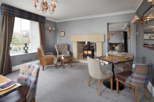 Una sala de estar con mesa y sillas y una chimenea. en The Dunstanburgh Castle Hotel, en Embleton