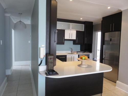 a kitchen with black cabinets and a bowl of fruit on a counter at Summerseas 58 in Port Elizabeth