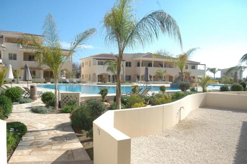 a resort with a swimming pool and palm trees at Aphrodite Sands Apartment D104 in Mandria