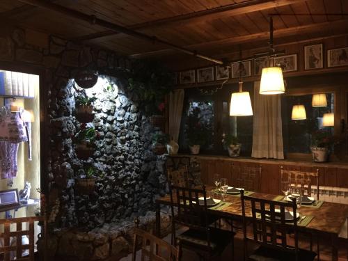a dining room with a table and chairs and a stone wall at Alojamientos Turisticos La Utrera in Las Majadas
