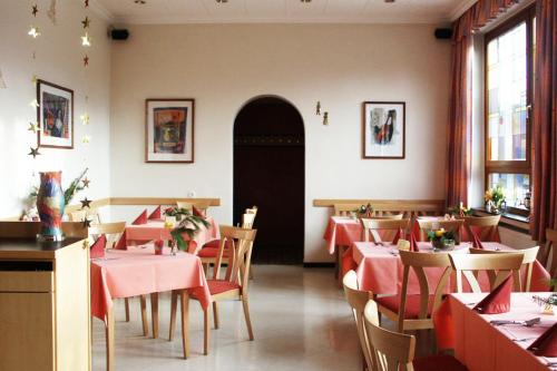 a restaurant with tables and chairs with red tablecloths at Hotel Alt Oesselse in Hannover