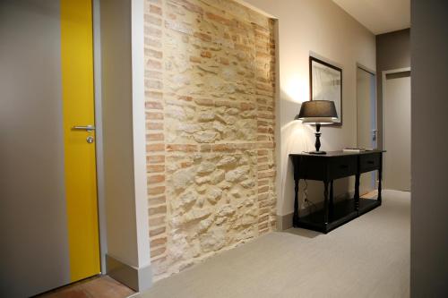 a hallway with a stone wall with a desk and a lamp at Appartements Numeroa in Albi