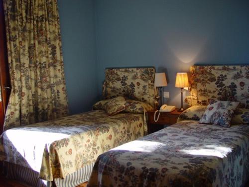 a bedroom with two beds and a lamp and a phone at La Puerta de la Ribera in Sardón de Duero
