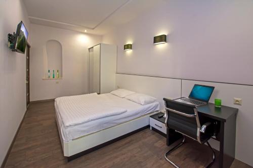 a bedroom with a bed and a desk with a laptop at Yerevan Hostel in Yerevan