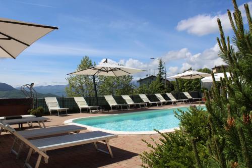 a swimming pool with lounge chairs and umbrellas at Albergo Ristorante Miramonti Toano in Toano