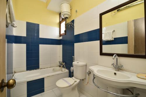 La salle de bains est pourvue de toilettes, d'un lavabo et d'un miroir. dans l'établissement Hotel Galaxy, à Dehradun