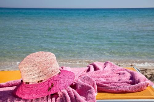 a pink hat sitting on a towel on the beach at Mira Spiaggia in San Vito lo Capo