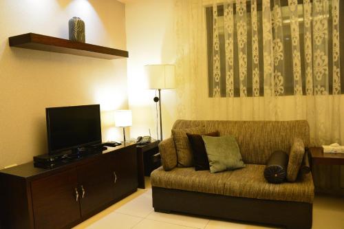 a living room with a couch and a flat screen tv at Nadine Hotel Suites in Amman